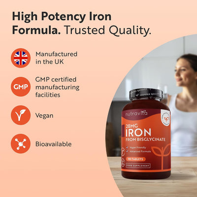 A bottle of Nutravita 28MG Iron supplement on a wooden surface, with a blurred woman in a kitchen in the background and marketing text and icons on the left highlighting UK manufacturing, GMP certification, vegan status, and bioavailability.
