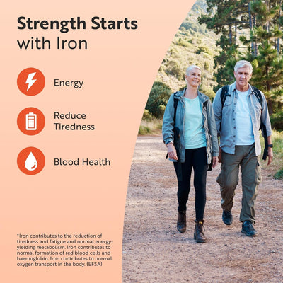 Promotional graphic with the headline 'Strength Starts with Iron' on a peach background, listing benefits: Energy, Reduce Tiredness, Blood Health. A photo of an older couple walking on a forest path appears on the right side with a small disclaimer about iron and red blood cell formation.