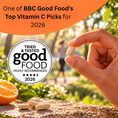A hand holds a single vitamin C tablet over a stone surface with other tablets nearby, outdoors with a blurred garden background. An orange banner at the top reads 'One of BBC Good Food's Top Vitamin C Picks for 2026,' and a circular badge says 'Tried & Tested Good Food Highly Recommended 2026.