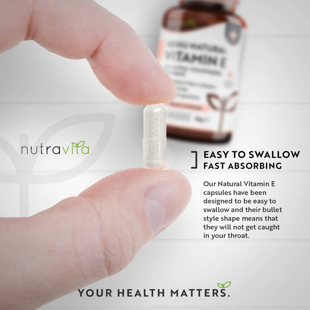 Hand holding a vitamin E capsule with Nutravita branding and product description.